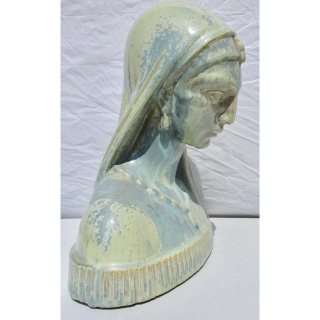 Female head in classical robes and decoration. Glazed over substantial ceramic builders clay core. Soft spreading blues...