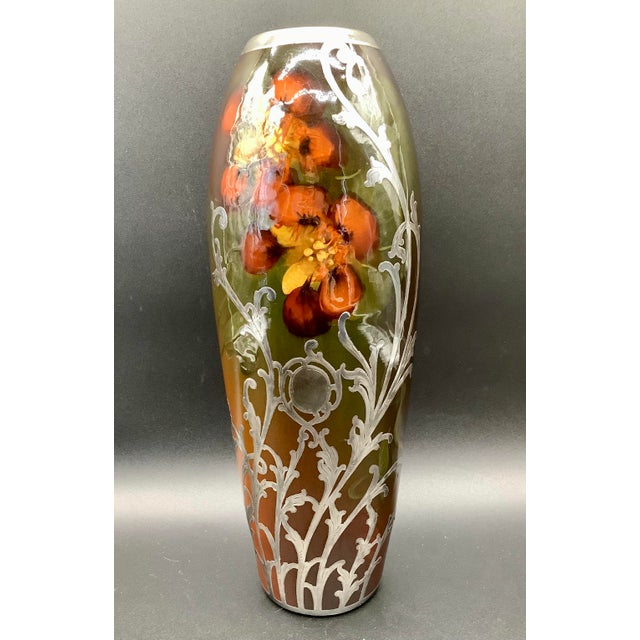 This vase features hand-painted flowers under a standard glaze, Sterling silver overly in an engraved floral scroll work.