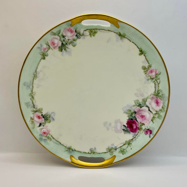 A classically designed small serving plate with a light green border punctuated with roses in delicate shades of pink and...