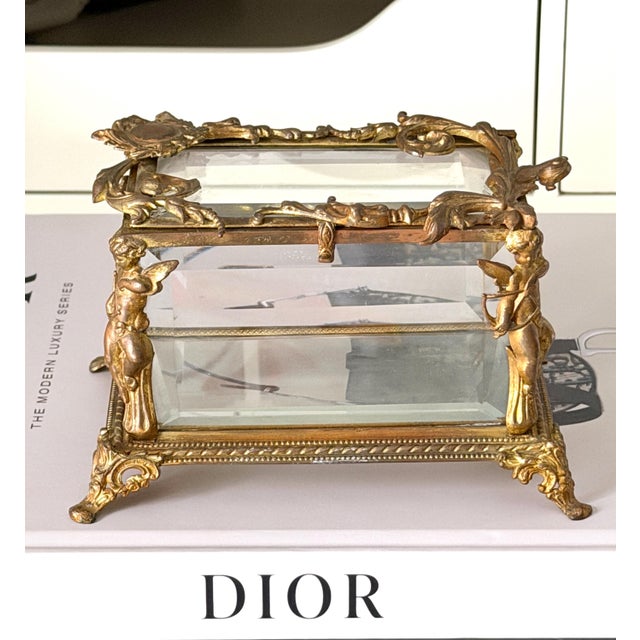 This is quite a unique jewelry box with gilt bronze cherubs guarding the 4 corners plus ornate bronze decor on the lid....