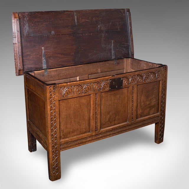 This is an antique coffer. An English, carved oak three panel linen chest or bay window seat, dating to the early Georgian...