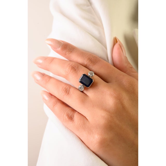 This elegant Art Deco-style three-stone ring features 1 octagon cut blue sapphire totaling 3.33 carats, set in rich 18K...