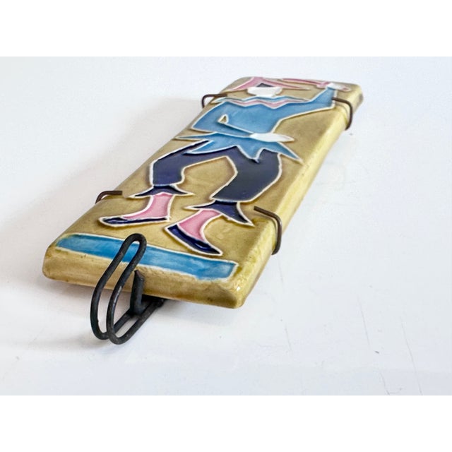 Decorative wall tile with a colorfully glazed relief of a stylized figure from the Commedia dell'arte, executed in vibrant...