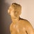An elegant terracotta sculpture depicting a young, nude woman standing against a rocky outcrop draped in fabric. Her...