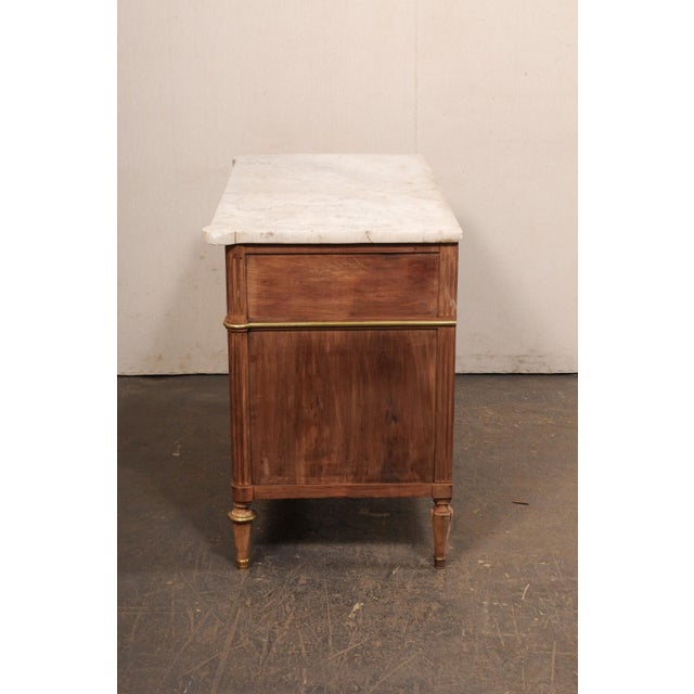 A French Neoclassical commode, with its original marble top and brass accents, from the 19th century. This antique chest...