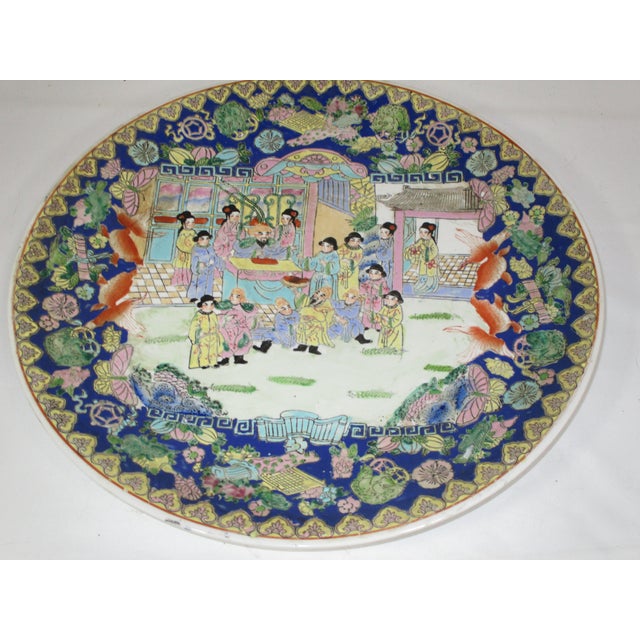 A large Chinese porcelain rose Mandarin charger, hand-painted in enamel colors of royal blue, rose, yellow and teal. It is...