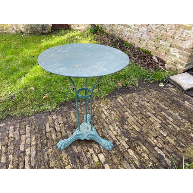 A whimsical bistro or garden table from France, dating from the 1900s. This table features a cast-iron base and an iron...