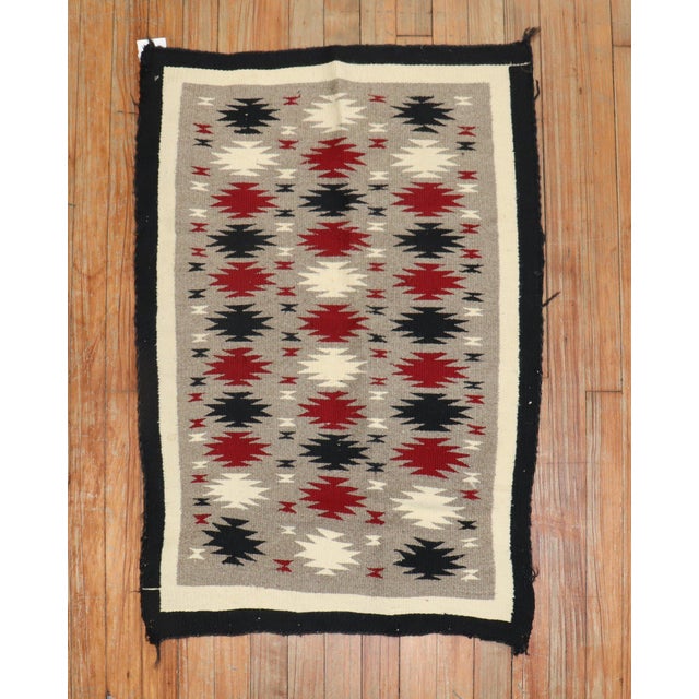 A highly decorative 20th-century American Navajo rug with an all-over geometric tribal pattern on a grey field. Measures:...
