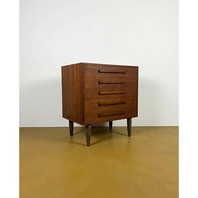 A pair of danish chests of drawers, 1960s. Teak frame with tapered, light-colored wood legs. Each drawer features five...
