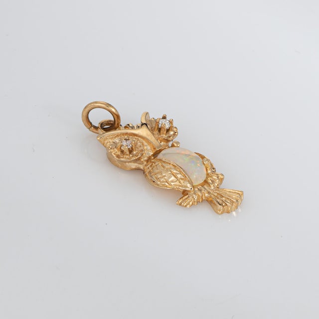 Sweet owl pendant set with diamond eyes and an opal belly, is crafted in 14 karat yellow gold. Two small diamonds total an...
