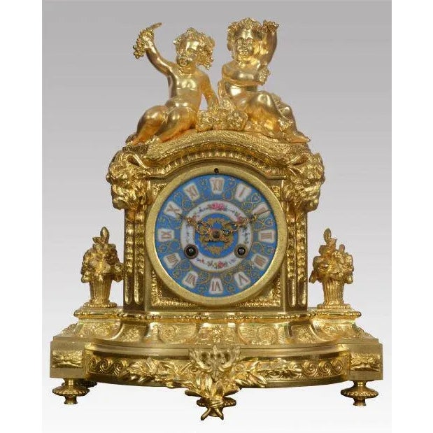 French gilt mantel clock, decorated in the rococo style the case surmounted with a pair of cherubs above circular painted...