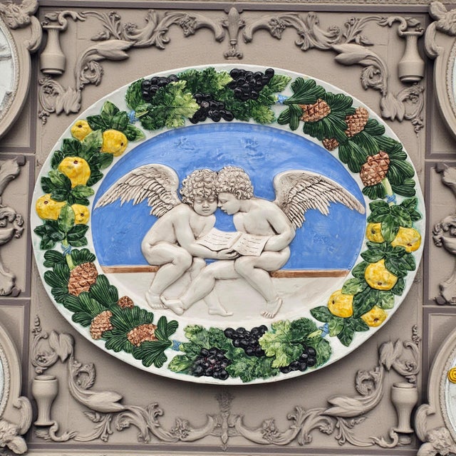 Italian decorative wall platter executed in the Della Robbia revival idiom, featuring two winged putti reading within a...