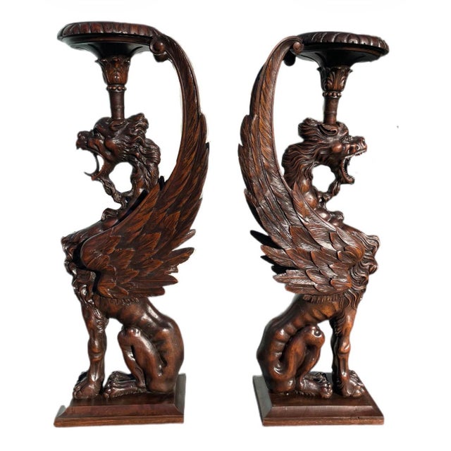 An exceptional and highly sculptural pair of hand-carved griffin pedestal stands, executed in richly toned dark wood and...