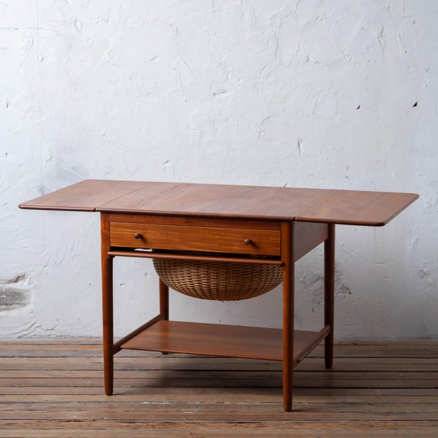A teak sewing table designed by Hans J. Wegner for Andreas Tuck, model AT-33, produced in Denmark in the 1960s. Two drop-...