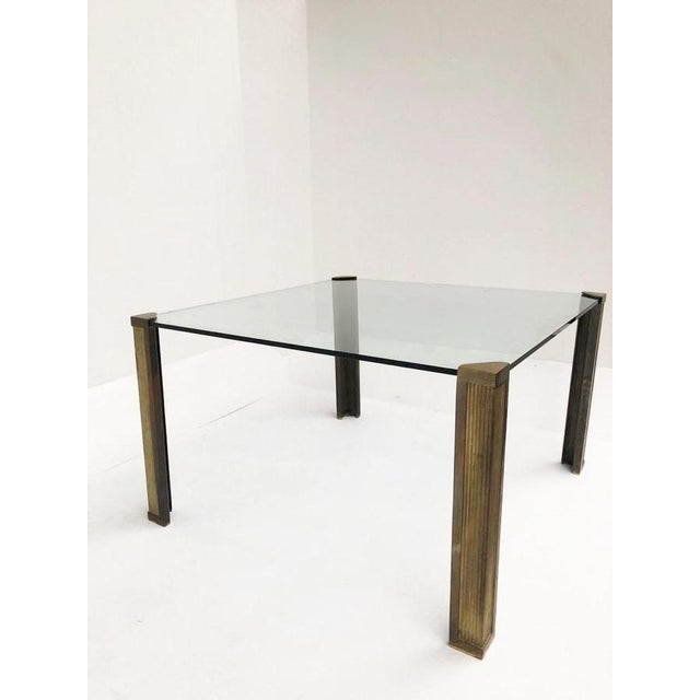 Impressive square glass dining table with cast bronze legs designed by Peter Ghyczy. The thick glass top is supported in...