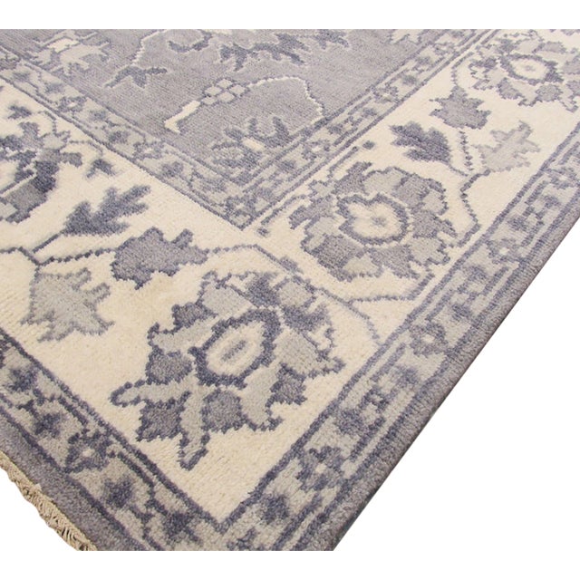 A hand-knotted wool rug in a traditional Oriental design, made in India and measuring 9' x 12'. Floral drawing across the...