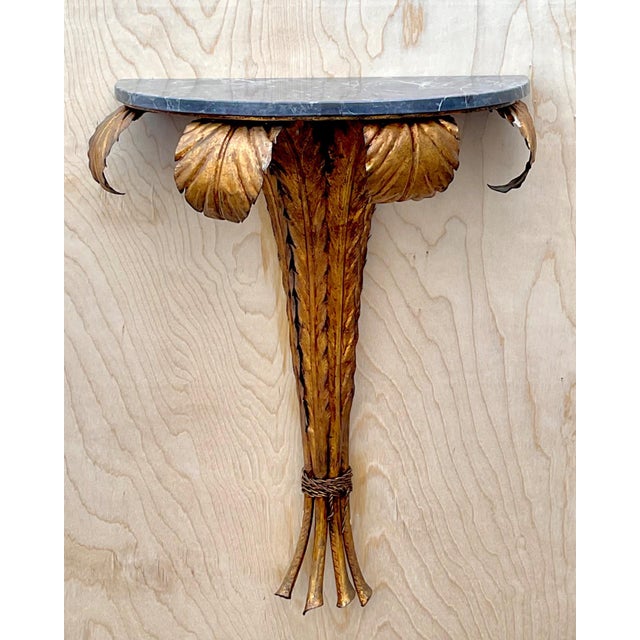 This vintage gilt metal wall console pairs sculptural, nature-inspired ironwork with the quiet luxury of a demi-lune...