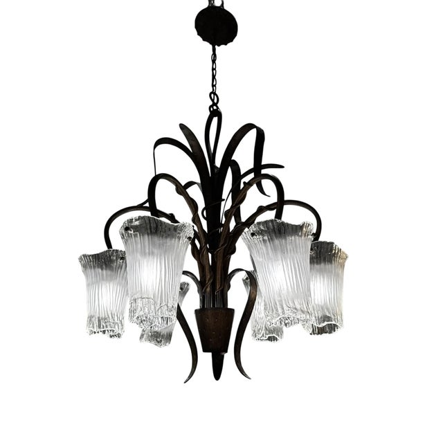 A striking Art Deco–inspired chandelier featuring a sculptural wrought iron frame paired with six fluted glass shades. The...