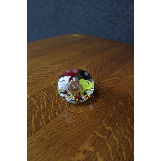 Handcrafted art glass paperweight featuring a bouquet of colorful lampwork flowers in white, red, black, yellow, and...