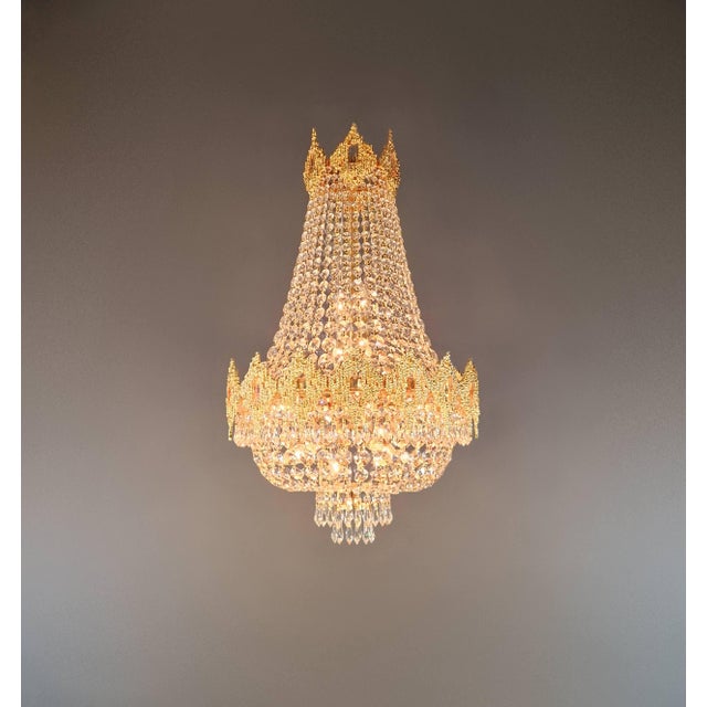 An elegant chandelier featuring a dense crystal structure and a distinctive shape. Its tapering form and decorative upper...