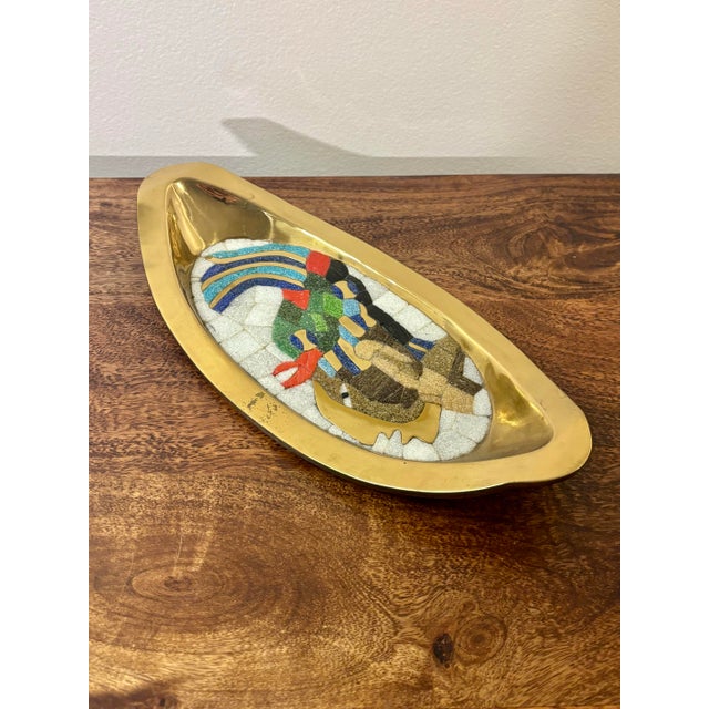 A striking Mid-Century Modern hand-wrought brass tray by Salvador Teran, featuring a vibrant mosaic glass depiction of...