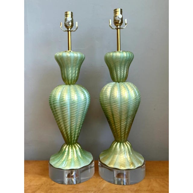 Showcasing masterful Italian craftsmanship, this exceptional pair of mid-century Murano table lamps features elegantly...