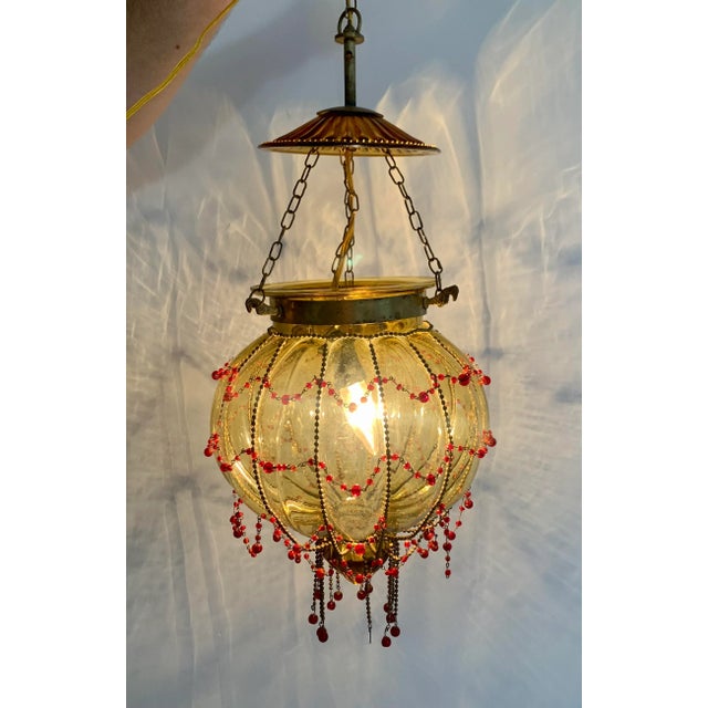 Vintage, caged glass ceiling lamp in a warm yellow with the caging being emphasized by red, hand blown glass and brass...