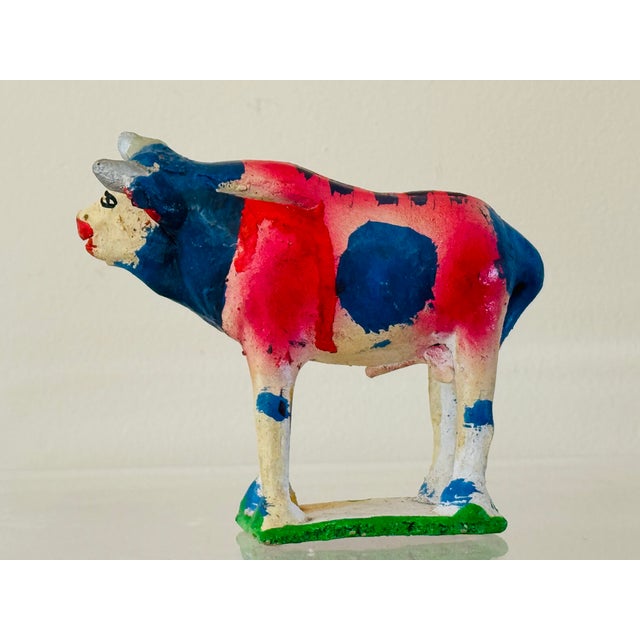 A whimsically glazed pottery cow. A slot along the back allows for coins and to function as a bank. From Mexica circa 1940.