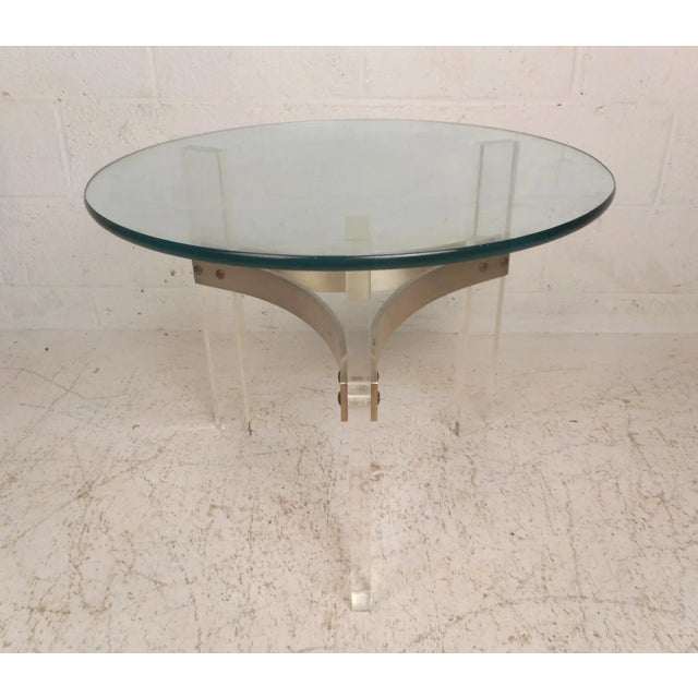 This unique vintage modern end table features a tripod lucite base and a thick round glass top. The sturdy base is secured...