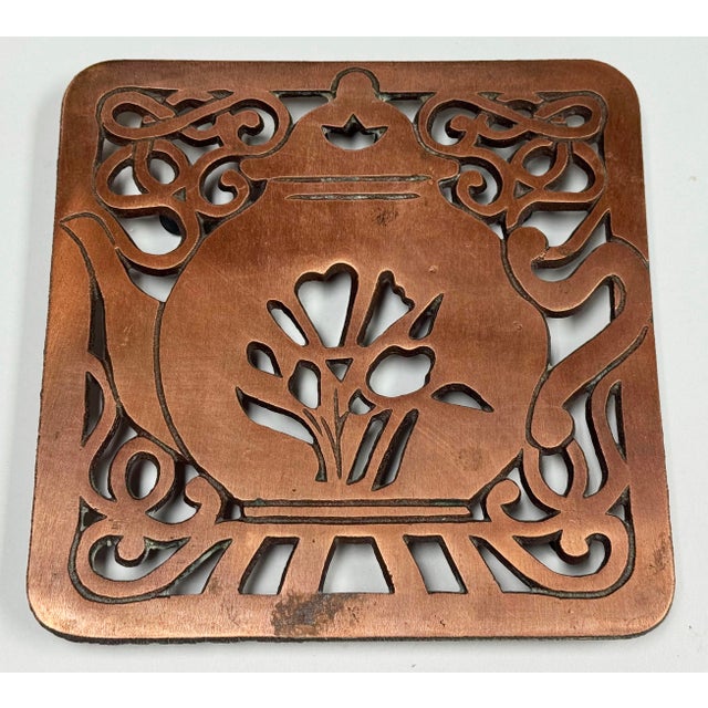 Vintage copper and cast iron tea kettle motif trivet. Hanging hardware on the back and rubber pads to the feet. Marked...