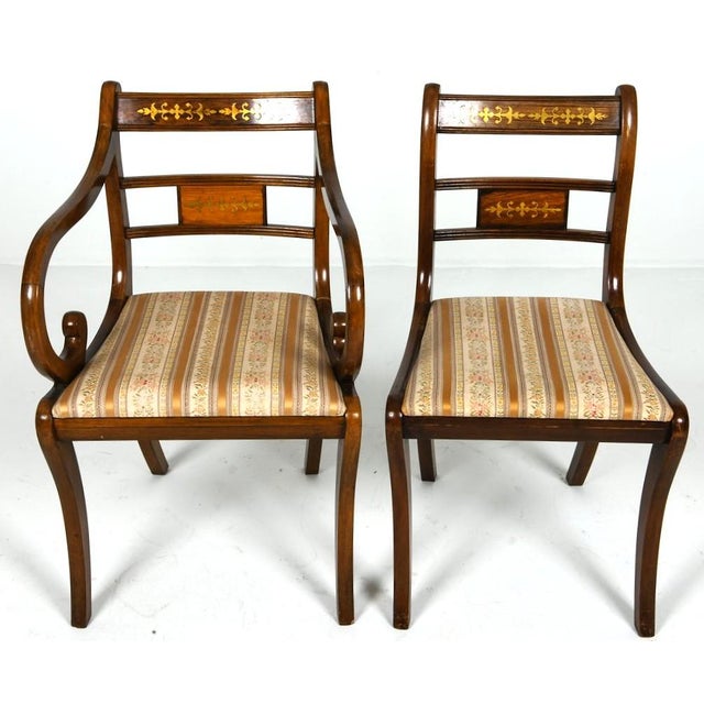 A set of 8 fine English Regency style dining chairs with brass inlay and saber front legs. An elegantly constructed wood...