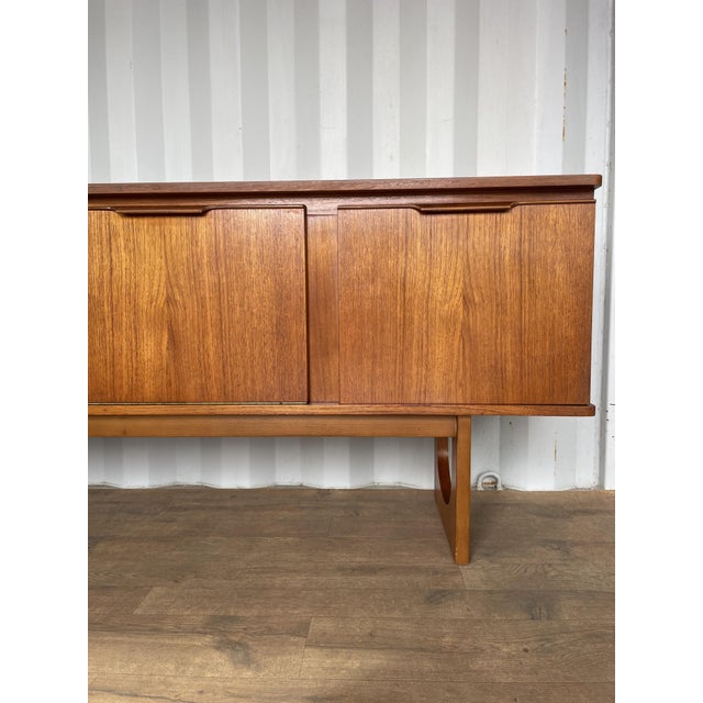 This elegant mid-century teak sideboard by Stonehill Furniture showcases the refined craftsmanship and Scandinavian...