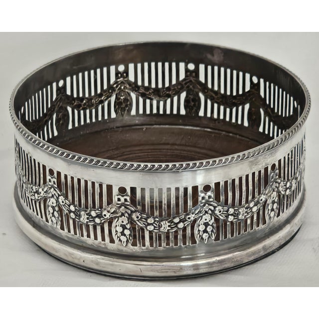 A beautifully detailed Edwardian silver plated wine bottle coaster from Sheffield, England, dating to the early 20th...
