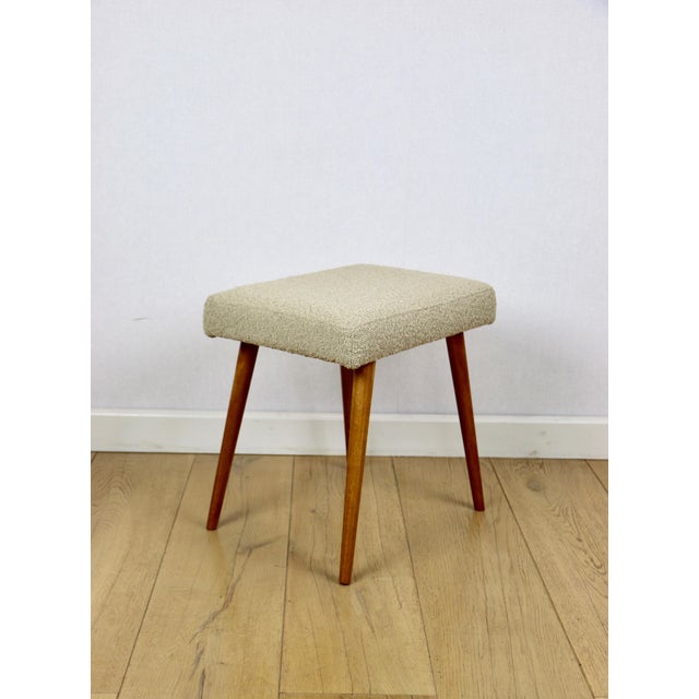 Bouclé stool seat in beige with round beech legs. This vintage stool was manufactured in the 1970s. Completely...