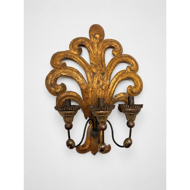 A dramatic pair of Italian Baroque Revival gilt tole three-light wall sconces. Each is comprised of 19th century elements...