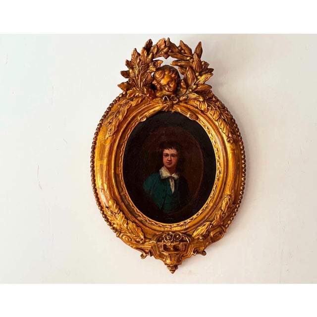 A captivating antique portrait painting dating to the 19th century (1800s), depicting a young boy dressed in a blue coat...