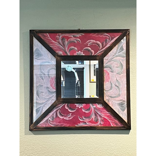 This striking 23" x 23" vintage Peruvian reverse painted glass mirror features a vibrant, hand-painted floral and foliate...