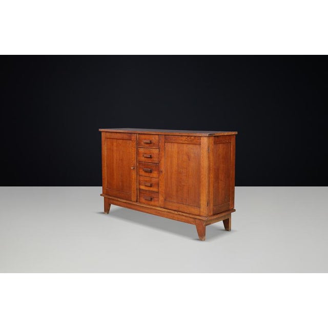 René Gabriel Patinated Oak Sideboard, France, 1940s This mid-century sideboard, crafted from patinated French oak, was...