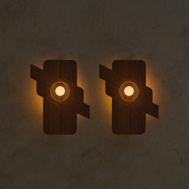 A pair of 1970s French wall sconces in the manner of Maison Regain, crafted in warm elm. Graphic and sculptural in form,...