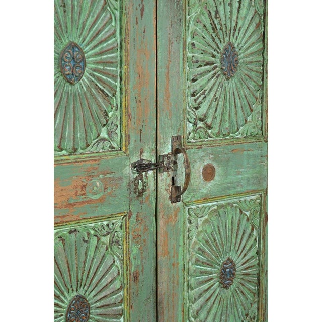 This Antique Indian Painted Teakwood Small Armoire is handcrafted from solid teakwood, featuring four carved sunburst door...