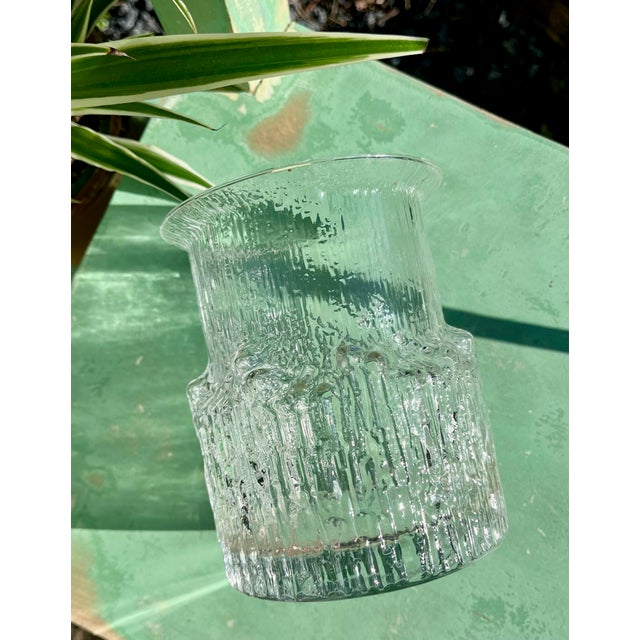 An elegant Arnica vase in clear glass, designed by the renowned Finnish designer Tapio Wirkkala for Iittala in 1975. The...