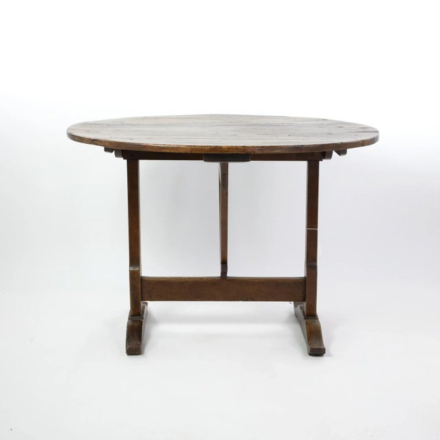 A provincial round vendange tilt top table with beautiful, richly-grained plank top and trestle supports, French circa...