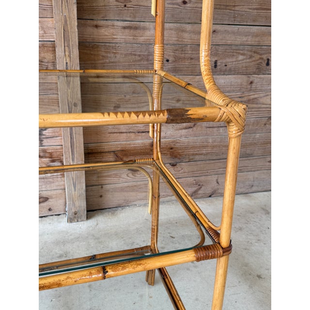 A striking vintage rattan étagère featuring a dramatic Brighton Pavilion–style fan crest and four glass display shelves....