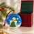 Delightful vintage glass Christmas ornament featuring a whimsical snowman decorating a Christmas tree beneath a vivid blue...