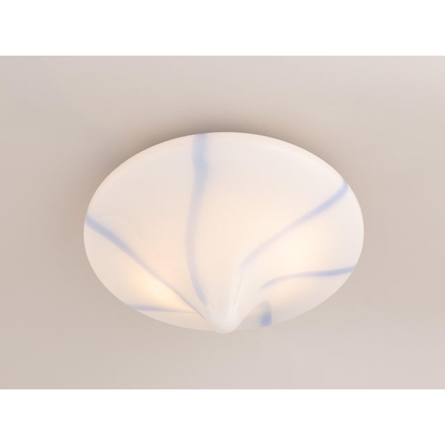 An elegant Italian flush mount or wall sconce from the 1960s–70s, featuring a hand-blown glass shade in white with blue...