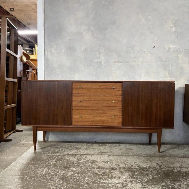 A handsome mid-century sideboard by Wrighton, featuring an attractive two-tone combination of warm teak and darker walnut-...