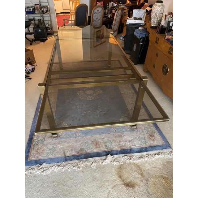 Beautiful brass and glass extension dining table, very rare and useful integrated leaf. Smoky glass panels. Great...