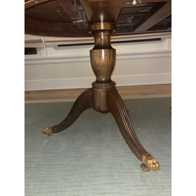 Antique French oval dining table with molded skirt raised on a pedestal ending in tripod legs capped by brass casters....