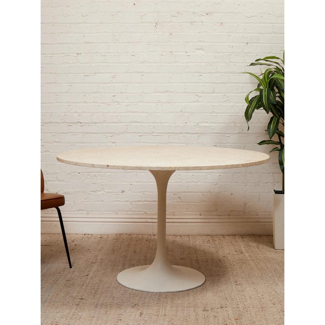 A beautifully streamlined vintage dining table featuring a substantial round travertine top paired with a sculptural white...