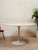 A beautifully streamlined vintage dining table featuring a substantial round travertine top paired with a sculptural white...